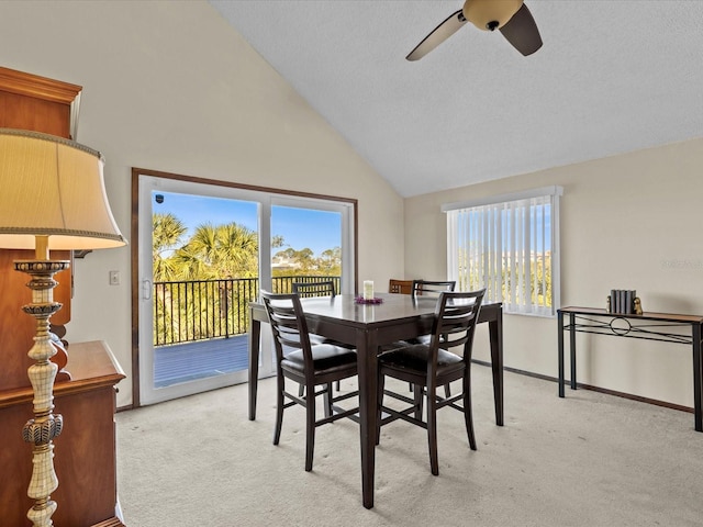 carpeted dining space with ceiling fan and lofted ceiling