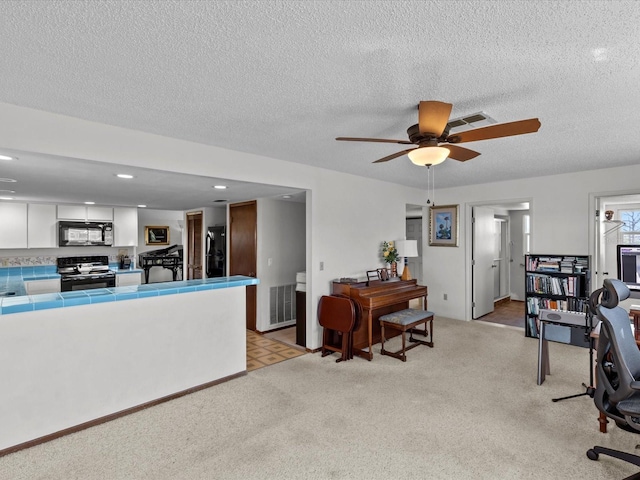 interior space featuring white cabinets, tile counters, black appliances, and light carpet