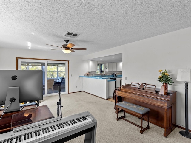 miscellaneous room featuring ceiling fan, light carpet, and a textured ceiling