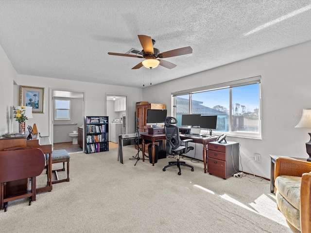 home office with a textured ceiling, ceiling fan, light carpet, and washer / clothes dryer