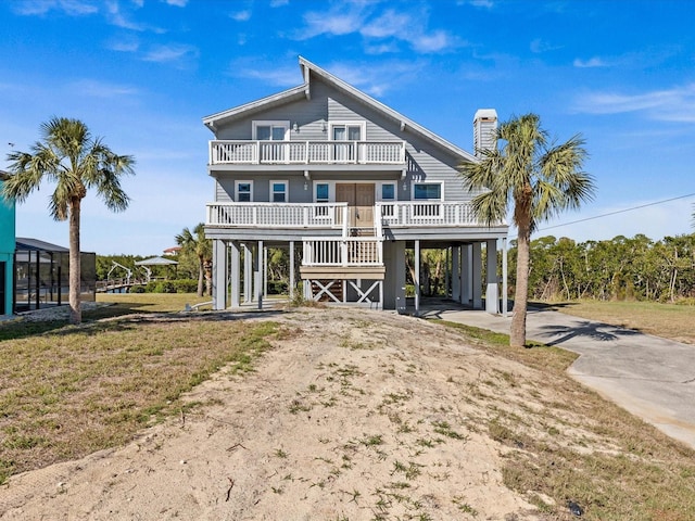 back of house featuring a yard, a balcony, and a carport