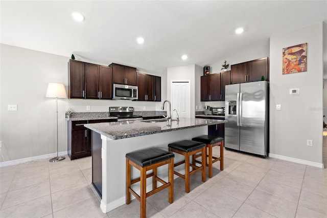 kitchen featuring a kitchen breakfast bar, sink, an island with sink, dark brown cabinetry, and stainless steel appliances