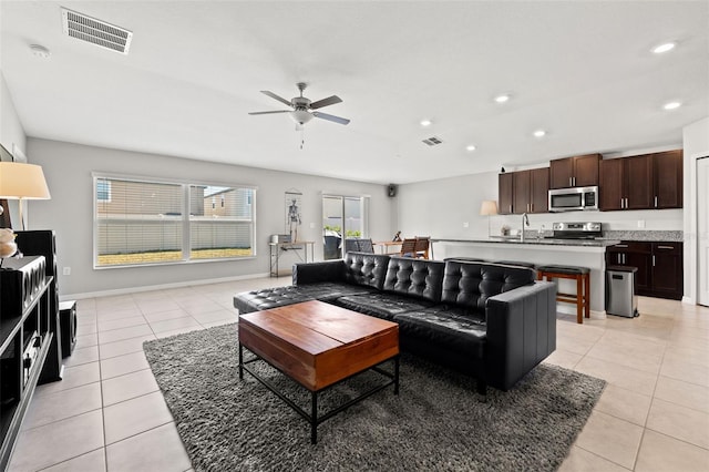 tiled living room featuring ceiling fan and sink