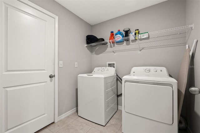 clothes washing area with washer and clothes dryer and light tile patterned floors