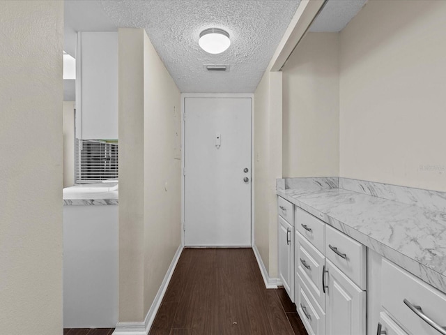 hall featuring a textured ceiling and dark wood-type flooring