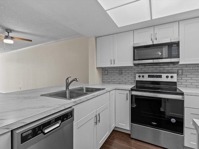 kitchen with appliances with stainless steel finishes, dark hardwood / wood-style flooring, a textured ceiling, sink, and white cabinetry