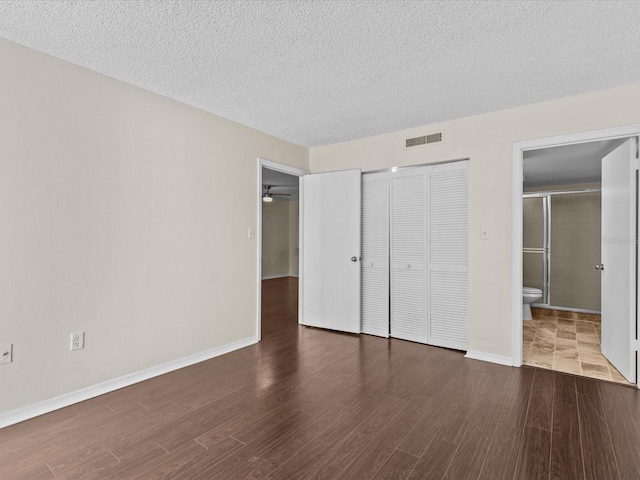 unfurnished bedroom featuring a textured ceiling, connected bathroom, and a closet