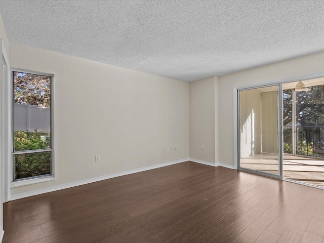 empty room with dark hardwood / wood-style floors and a textured ceiling