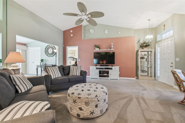 carpeted living room featuring ceiling fan with notable chandelier, high vaulted ceiling, and baseboards