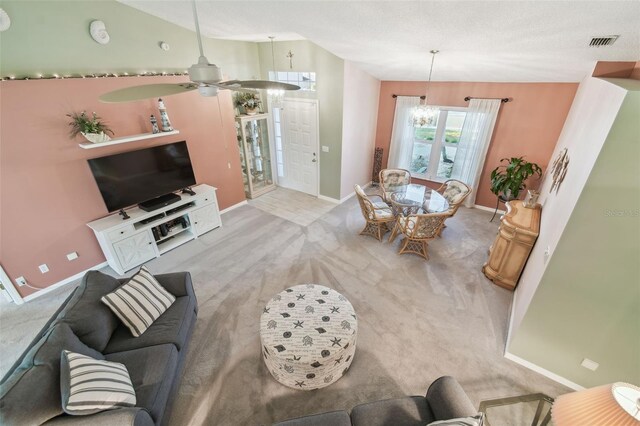 living room with light carpet, baseboards, visible vents, and lofted ceiling