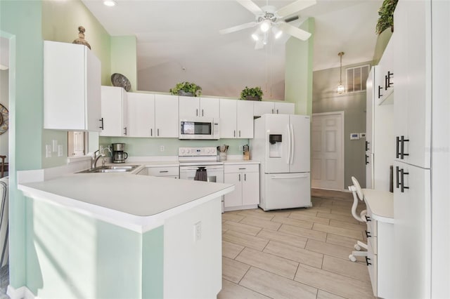 kitchen with a peninsula, white appliances, a sink, white cabinets, and light countertops