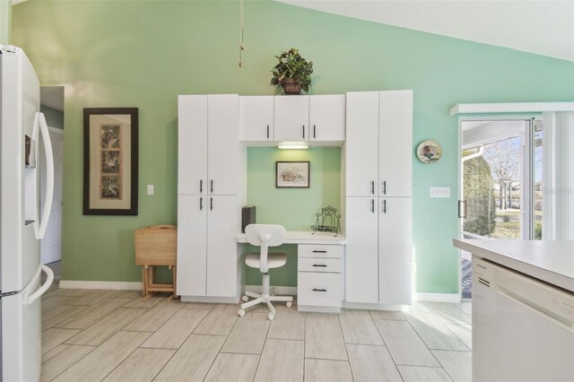 kitchen featuring white appliances, vaulted ceiling, white cabinetry, and light countertops