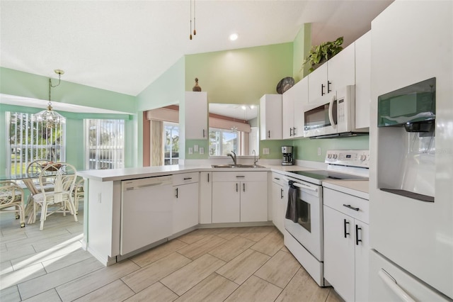 kitchen featuring a peninsula, white appliances, white cabinetry, light countertops, and decorative light fixtures