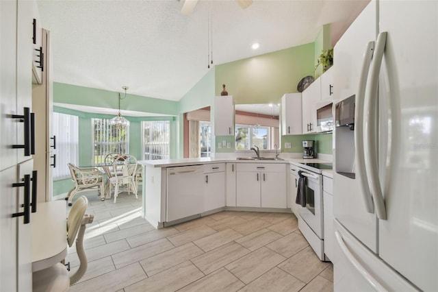 kitchen featuring white appliances, light countertops, hanging light fixtures, and white cabinetry