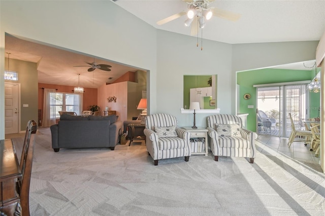 living area with high vaulted ceiling, ceiling fan with notable chandelier, and light colored carpet