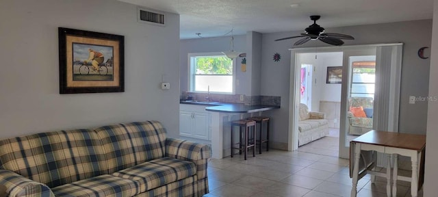 tiled living room featuring a textured ceiling, ceiling fan, and sink