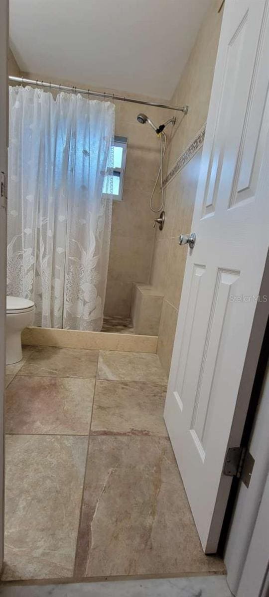 bathroom with a shower with curtain and toilet