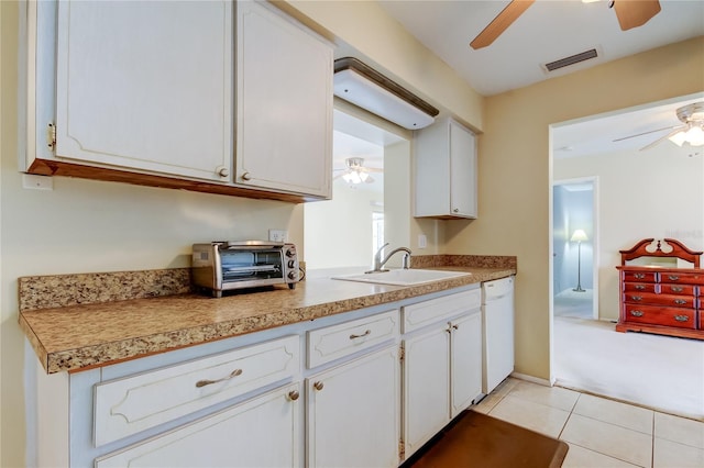 kitchen featuring white cabinets, light tile patterned floors, dishwasher, and sink