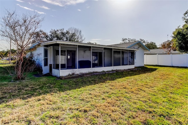 rear view of house with a lawn and a sunroom