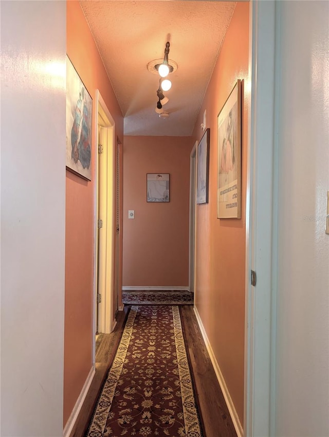 corridor featuring dark hardwood / wood-style flooring and a textured ceiling