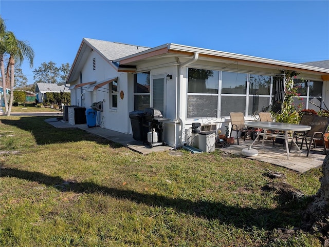 back of property featuring a sunroom, a patio area, and a lawn