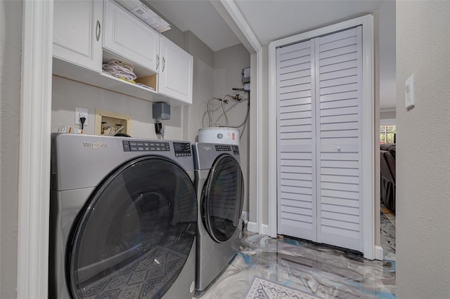 clothes washing area with washer and dryer and cabinets