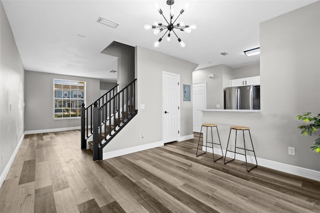 interior space featuring white cabinetry, an inviting chandelier, electric panel, stainless steel fridge, and a kitchen bar