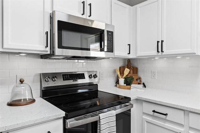 kitchen featuring decorative backsplash, light stone countertops, white cabinetry, and appliances with stainless steel finishes