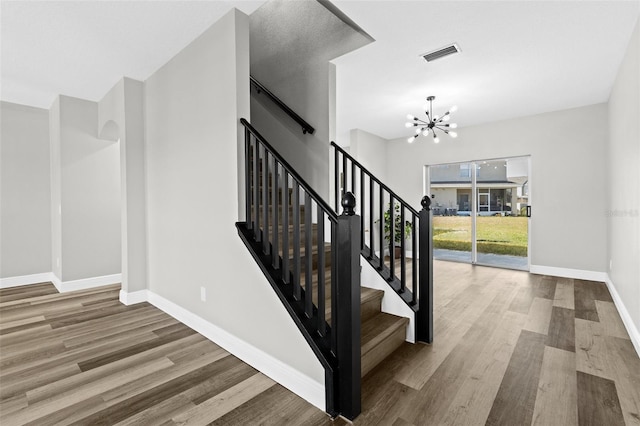 staircase featuring hardwood / wood-style floors and an inviting chandelier