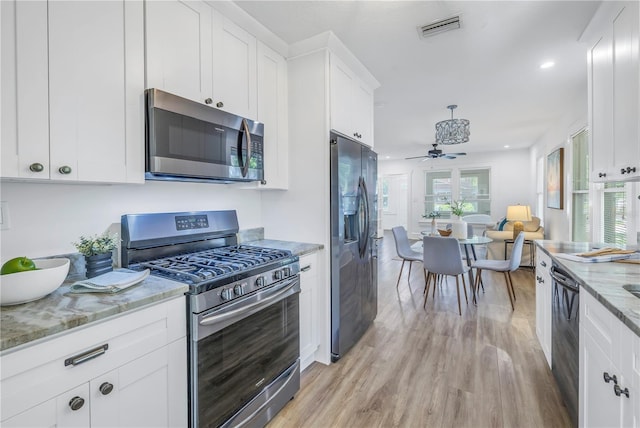 kitchen with light stone countertops, white cabinetry, ceiling fan, black appliances, and light wood-type flooring