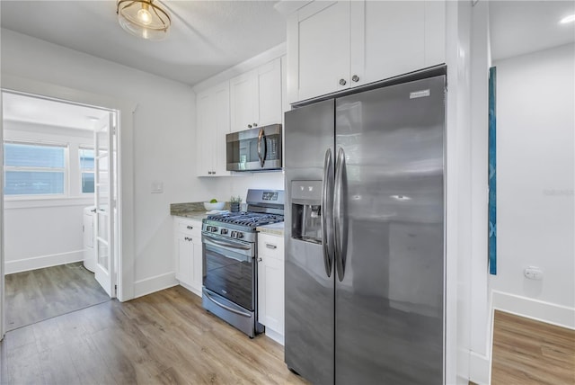 kitchen featuring light stone countertops, white cabinetry, stainless steel appliances, and light hardwood / wood-style flooring