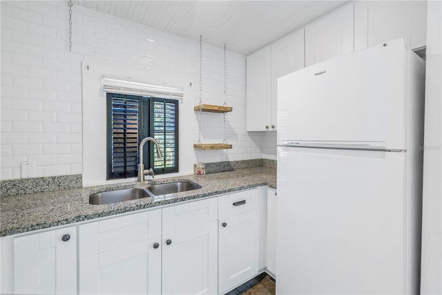 kitchen featuring tasteful backsplash, sink, stone countertops, white cabinets, and white fridge