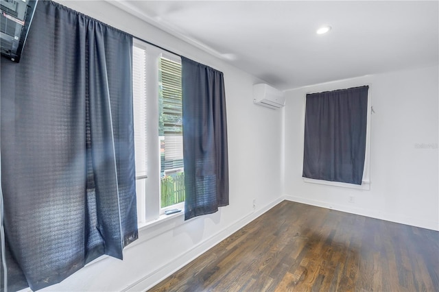 unfurnished room with an AC wall unit, dark wood-type flooring, and a healthy amount of sunlight