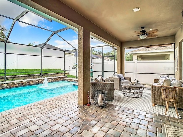 pool with a ceiling fan, a patio, glass enclosure, fence, and an outdoor living space