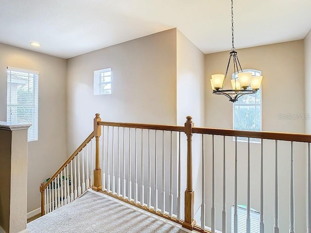 staircase with a wealth of natural light and an inviting chandelier