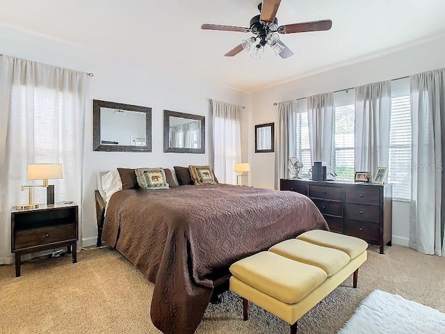 bedroom with a ceiling fan, light carpet, and baseboards