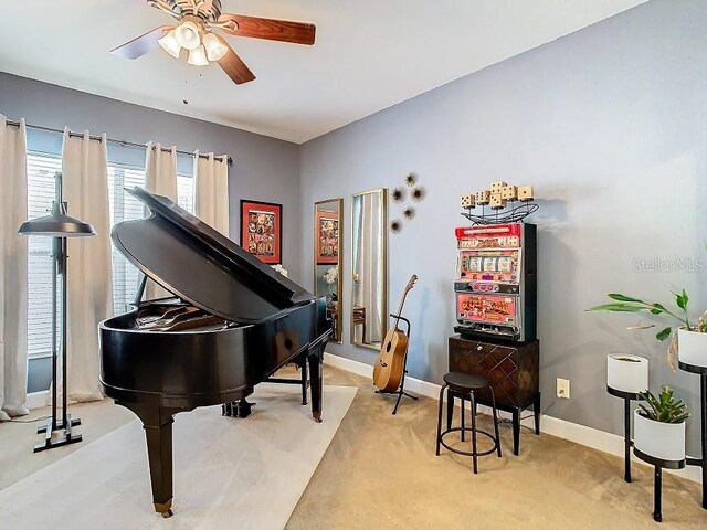 sitting room with ceiling fan, baseboards, and light colored carpet