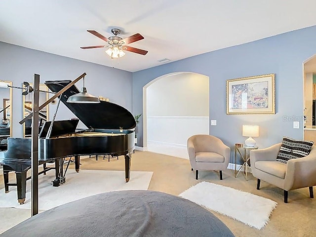 living area with arched walkways, visible vents, carpet flooring, ceiling fan, and baseboards