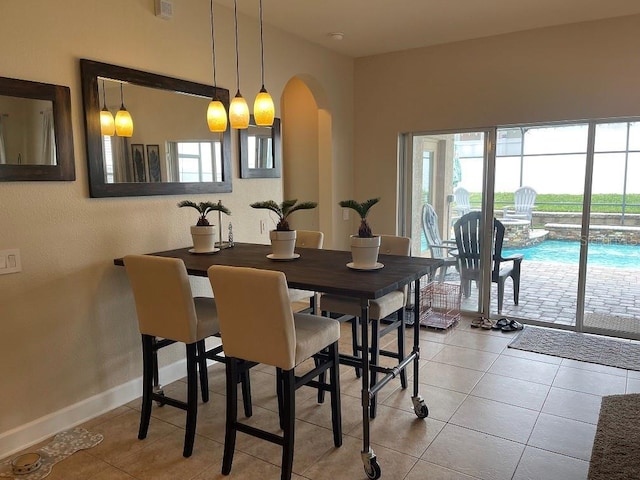 dining room featuring light tile patterned floors, arched walkways, and a wealth of natural light