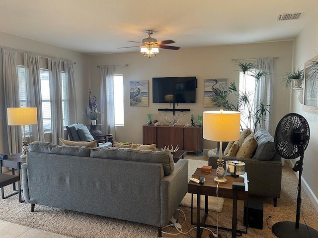 living area with baseboards, visible vents, and a ceiling fan