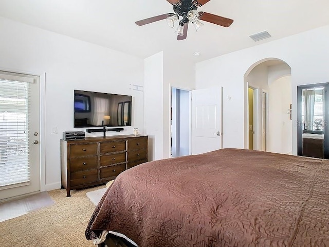 bedroom with arched walkways, light carpet, visible vents, and a ceiling fan