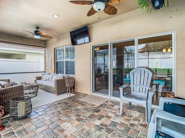 view of patio / terrace with a ceiling fan, fence, and an outdoor living space