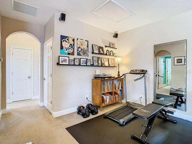 workout area featuring attic access, visible vents, arched walkways, baseboards, and carpet