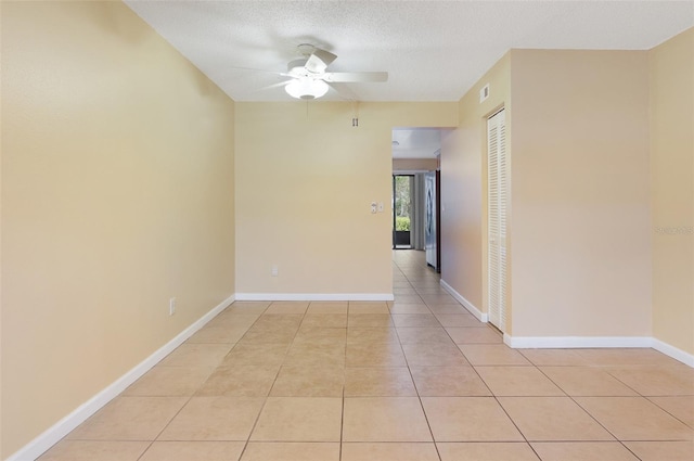 unfurnished room with ceiling fan, light tile patterned flooring, and a textured ceiling