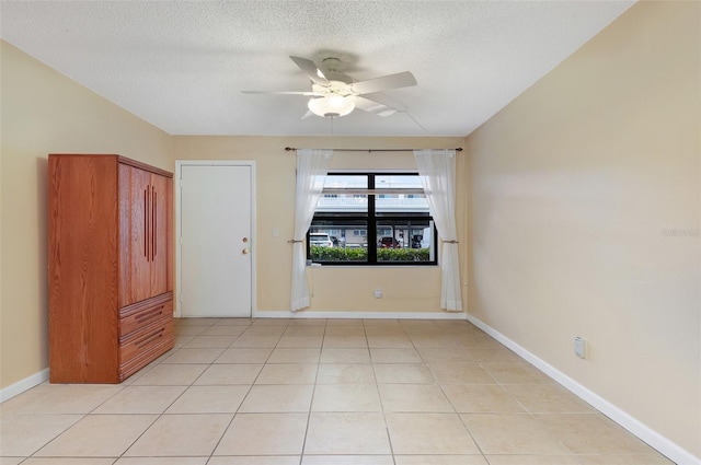 spare room with light tile patterned floors, a textured ceiling, and ceiling fan