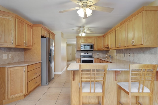 kitchen featuring sink, a breakfast bar area, light tile patterned flooring, kitchen peninsula, and stainless steel appliances