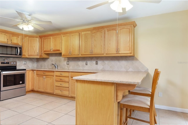 kitchen featuring backsplash, a breakfast bar area, light tile patterned floors, kitchen peninsula, and stainless steel appliances