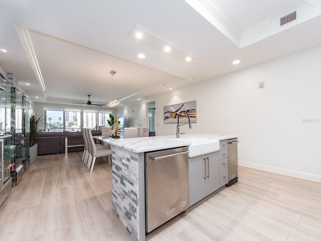 kitchen featuring dishwasher, a kitchen island with sink, and a tray ceiling