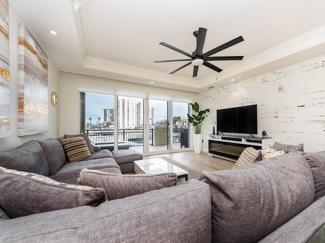 living room featuring ceiling fan, light hardwood / wood-style floors, crown molding, and a tray ceiling