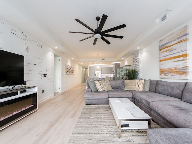 living room with light hardwood / wood-style flooring, ceiling fan, and ornamental molding